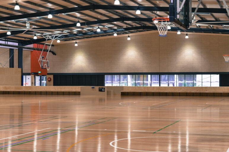 Indoor multi-court stadium at Eagle Stadium, Wyndham, featuring polished timber floors, basketball hoops, and seating along the sidelines.
