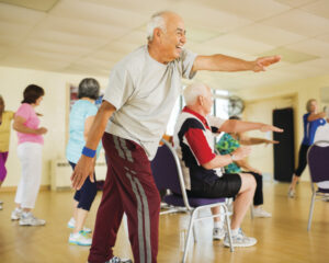 Older adults enjoying a chair-based fitness session at WynActive, moving arms and legs with guided support.