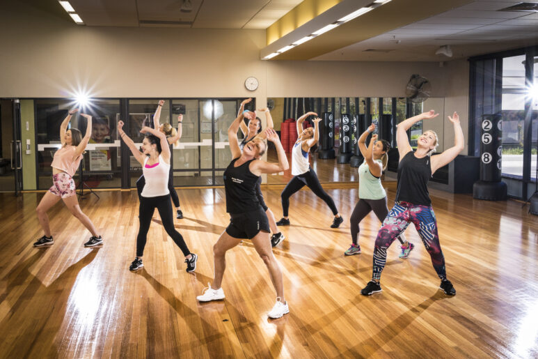 Group fitness dance class at Eagle Stadium with participants moving energetically in a mirrored studio.