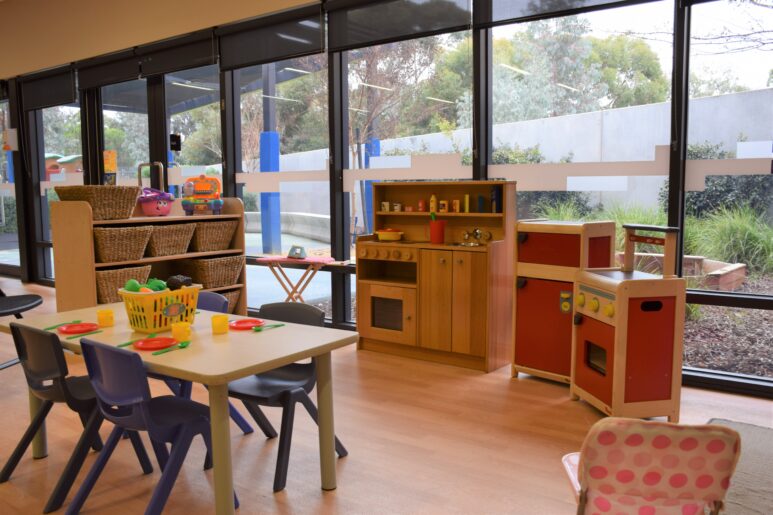 Playroom with toy kitchen sets, baskets of toys, and a child-sized dining table with play food.