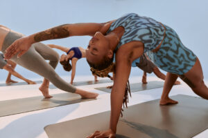 Group class practising yoga poses on mats, with one woman arching into a side stretch.