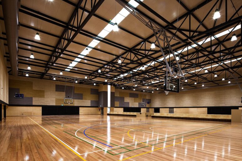 Spacious indoor basketball court at Eagle Stadium with polished timber floors, overhead lighting, and retractable hoops.