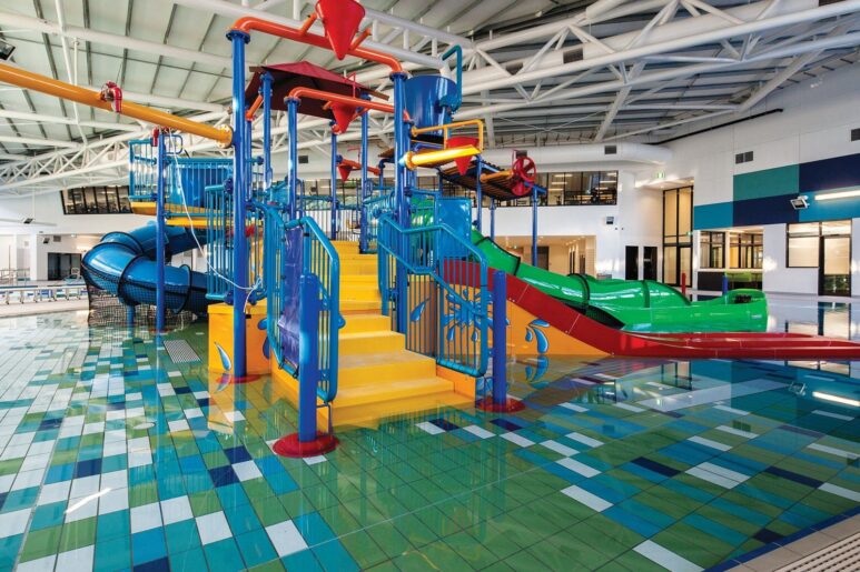 Indoor water play structure at AquaPulse Hoppers Crossing featuring colourful slides, tipping buckets, and splash features.