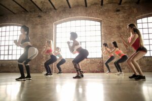 Group fitness class in a loft-style studio performing squats together.